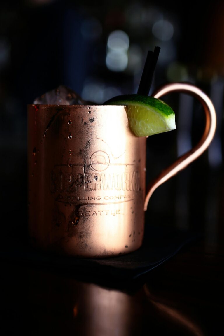 Close-up of a copper mug cocktail garnished with a lime slice, set in a dimly lit environment.