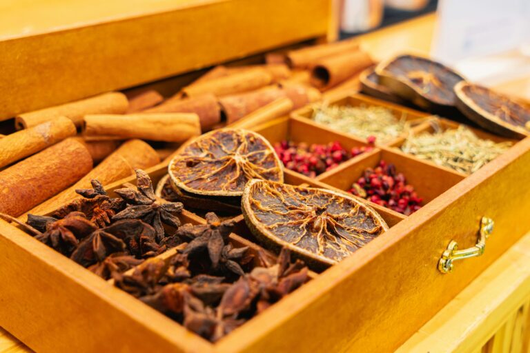 Close-up of various spices in a wooden box, including dried citrus, cinnamon, and star anise.